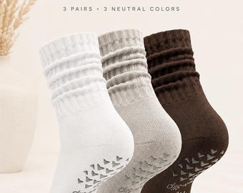 May include: Three pairs of slouch socks in white, stone gray, and coffee brown. Each sock features a ribbed cuff, a slouchy leg, and a non-slip grip pattern on the sole. The text reads Cozy Slouch Socks, 3 Pairs, 3 Neutral Colors, Classic White, Stone Gray, and Coffee Brown.