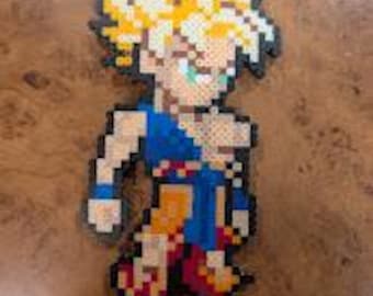 May include: A pixel art figure crafted from small plastic beads depicting a character with spiky yellow hair, wearing a blue and orange martial arts uniform. The figure features a defined outline and a grid-like texture characteristic of fuse bead art.