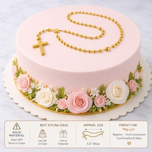 May include: A light pink cake decorated with a gold rosary and a floral border of pink and white roses, green leaves, and small white flowers. The rosary is approximately 5.5 inches wide. The cake is suitable for baptism, first communion, and confirmation.