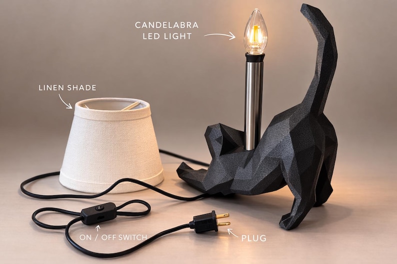 K&ouml;nnte beinhalten: Schwarze Katzen-Tischlampe mit Leinen-Lampenschirm. Die Lampe verf&uuml;gt &uuml;ber eine LED-Kerzenlicht-Gl&uuml;hbirne und einen Ein-/Ausschalter. Der Stecker ist ein Standardstecker.
