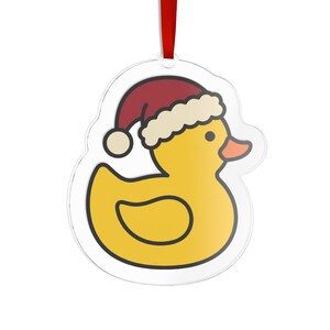 May include: A clear acrylic ornament shaped like a rubber duck wearing a red and white Santa hat. The duck is yellow with an orange beak and black outlines. A red ribbon is attached to the top for hanging, providing a festive holiday decoration.