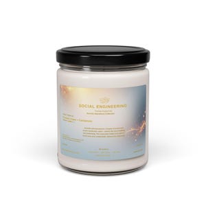 May include: A white candle in a glass jar with a black lid. The label reads "SOCIAL ENGINEERING" and lists "Coconut Cream + Cardamom" as the scent. The jar is on a white background.