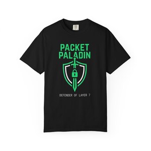 May include: Black t-shirt with a green and white graphic. The graphic features the words "PACKET PALADIN" above a shield design with a sword and lock, and the text "DEFENDER OF LAYER 7" below.