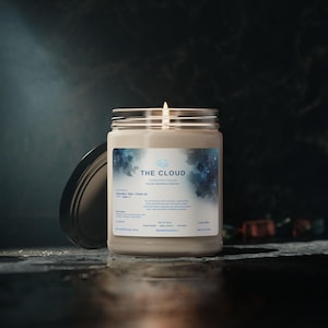 May include: A cream-coloured candle in a glass jar with a silver lid. The label reads "THE CLOUD" with a blue and white cloud graphic. The candle is part of the Sensory Operative Collection.