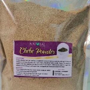 May include: A transparent bag containing beige powder. A purple label displays "NATURAL Chebe Powder" with details on use and benefits. The powder is for hair care, designed to help with moisture and length retention.