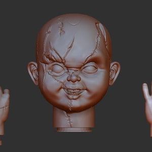 Puede incluir: Una cabeza de muñeca esculpida en marrón, con cicatrices cosidas y una sonrisa siniestra, flanqueada por dos manos separadas. La cabeza de la muñeca está centrada, con las manos a cada lado, sobre un fondo gris oscuro.