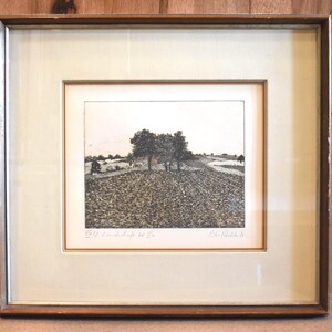May include: Framed landscape art print featuring a field with trees and a river. The artwork is in black and white, with a textured appearance. The frame is a dark brown wood with a cream-colored mat.