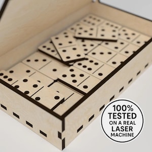 Può includere: Un set di domino in legno con punti neri, ordinatamente disposto all'interno di una scatola di legno colorata. La scatola ha un coperchio ed è tagliata al laser con bordi marrone scuro. L'immagine include un adesivo che dice "100% TESTATO SU UNA VERA MACCHINA LASER."