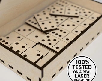 Puede incluir: Un juego de dominó de madera con puntos negros, ordenado dentro de una caja de madera de color claro. La caja tiene tapa y está cortada con láser con bordes marrones oscuros. La imagen incluye una pegatina que dice "100% PROBADO EN UNA MÁQUINA LÁSER REAL."
