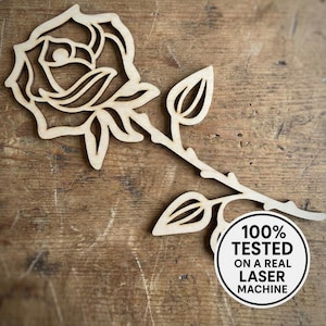 Può includere: Un ritaglio di rosa in legno con stelo e foglie, su una superficie di legno. La rosa ha petali dettagliati. Un adesivo circolare recita "100% TESTATO SU UNA VERA MACCHINA LASER".
