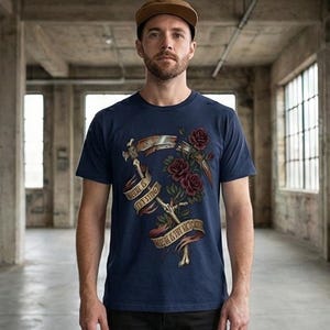 May include: Navy blue t-shirt featuring a graphic design with a scythe, roses, and banners. The banners read "Where is thy sting" and "Death is the victory". The design includes dark red roses and a bone-like scythe.