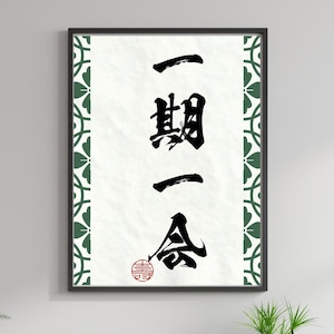 以下が含まれることがあります： 白地の背景に黒インクで書かれた日本の書道が特徴の額装アート。テキストは縦書きで、下部に赤い円形の印鑑が含まれています。フレームは黒色で、緑と白の模様のボーダーが付いています。