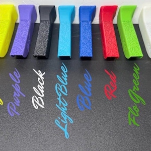 May include: A collection of ten colorful, textured plastic tools in shades of orange, yellow, purple, black, light blue, blue, red, green, white, and tan. Each tool has a curved design. The colors are labeled below each tool.
