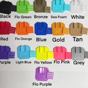 Peut inclure: Une collection d'objets imprim&eacute;s en 3D de diff&eacute;rentes couleurs : noir, vert, bronze, &eacute;cume de mer, blanc, rouge, orange, bleu, or, beige, violet, bleu clair, jaune, rose et gris. Chaque objet a une forme unique, avec les noms de couleurs en dessous.