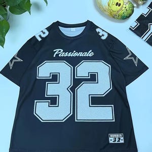 A black mesh football jersey with the number 32 and the word "Passionate" printed on it, along with a plant and a decorative item in the background.