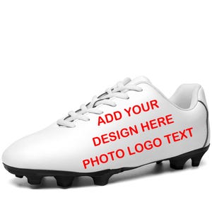 Peut inclure: Chaussure de football blanche avec crampons et lacets noirs. Le texte "ADD YOUR DESIGN HERE PHOTO LOGO TEXT" est imprimé en rouge sur le côté. La chaussure est conçue pour le sport.