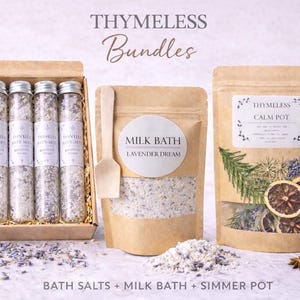 May include: A set of four glass tubes filled with bath salts in a cardboard box, a pouch labeled Milk Bath Lavender Dream with a wooden scoop, and a pouch labeled Calm Pot containing dried citrus slices, herbs, and star anise, with loose lavender.
