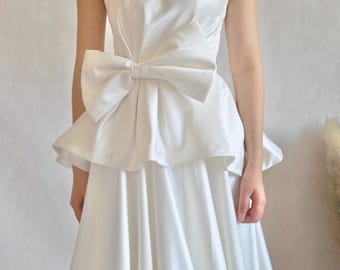 Vestido de novia de satén suave con lazo y sin tirantes.