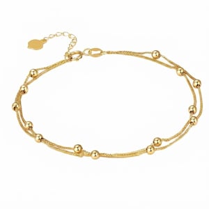 May include: A gold-toned double-strand chain bracelet featuring evenly spaced small round beads along the length. The bracelet includes a delicate extender chain with a small flat heart-shaped charm at the end and a secure lobster claw clasp.