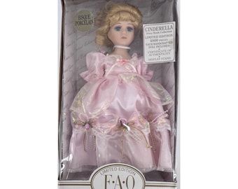 May include: A limited edition Cinderella doll in a display box. The doll has blonde hair, blue eyes, and wears a pink satin gown with lace and floral accents. The box includes a certificate of authenticity.