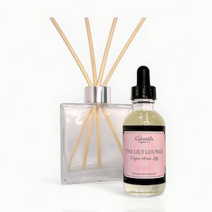 May include: A clear glass diffuser bottle with wooden reeds and a small glass bottle with a black dropper. The small bottle has a pink label that reads "THE LILY LOUNGE Wynn Asian Lily".