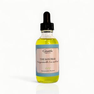 May include: A clear glass bottle with a black dropper top, filled with yellow liquid. The label reads "THE SANDBAR Margaritaville Sun and Soul" with the Columbia Fragrance Co. logo. The bottle is hand poured in Maryland.