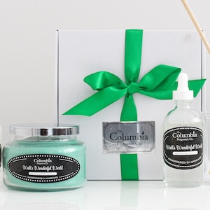 Puede incluir: Colección de productos de fragancia para el hogar, que incluye una vela, un ambientador en aerosol y un difusor, dispuestos sobre una superficie blanca. Los productos presentan etiquetas con el texto "Walls Wonderful World" y están empaquetados en una caja de regalo blanca atada con una cinta verde.