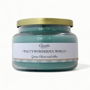 May include: A glass jar candle with a gold lid. The candle wax is a light teal color. The label reads "WALT'S WONDERFUL WORLD" and "Green Clover and Aloe". The Columbia Fragrance Co. logo is also visible.