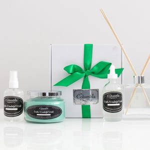 May include: A gift set of home fragrance products in a white box with a green ribbon. The set includes a candle, a diffuser, and a room spray. All products are labelled with the text "Columbia Fragrance Co." and the scent "Walla's Wonderful World".