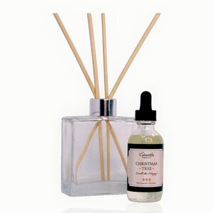 May include: A clear glass diffuser bottle with wooden reeds and a small glass bottle of fragrance oil. The fragrance oil bottle has a black dropper and a label that reads "Christmas Tree - Smell the Happy!" and "Hand poured in Maryland."