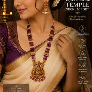 May include: A gold-toned necklace set featuring a large Gaja Lakshmi temple pendant with ruby kemp stones and pearl drops. The necklace consists of multiple strands of deep purple beads accented with gold elephant motifs. Matching jhumka earrings.