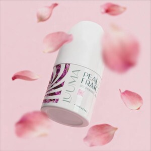Peut inclure: Un déodorant blanc avec le texte "PEAU FRAIC" et "IUUMA" en violet et blanc. Des pétales de fleurs roses flottent autour du déodorant sur un fond rose.