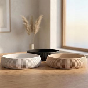 May include: A set of three ceramic mugs with a speckled, matte finish. The mugs are in shades of cream, light gray, and dark gray. Each mug has a simple, minimalist design, perfect for coffee or tea.