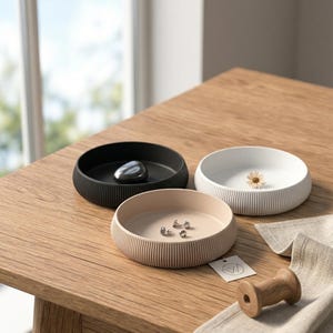 May include: A set of three ceramic mugs with a speckled, matte finish. The mugs are in shades of cream, light gray, and dark gray. Each mug has a simple, minimalist design, perfect for coffee or tea.