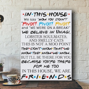 Könnte beinhalten: Weißes Leinwandbild mit Zitaten aus der Fernsehserie Friends, mit dem Text "IN THIS HOUSE". Der Text ist in verschiedenen Farben und Schriftarten gehalten, darunter "PIVOT!" in Rot, Blau und Gelb. Eine Kaffeetasse steht auf einer Holzoberfläche.