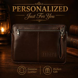 Könnte beinhalten: Eine braune Leder-Clutch mit Reißverschluss und Handschlaufe. Das Wort "mert" ist auf der Vorderseite eingeprägt. Der Text "PERSONALIZED Just For You" steht oben. Die Wörter "Genuine Leather" und "Perfect Gift" sind ebenfalls vorhanden.
