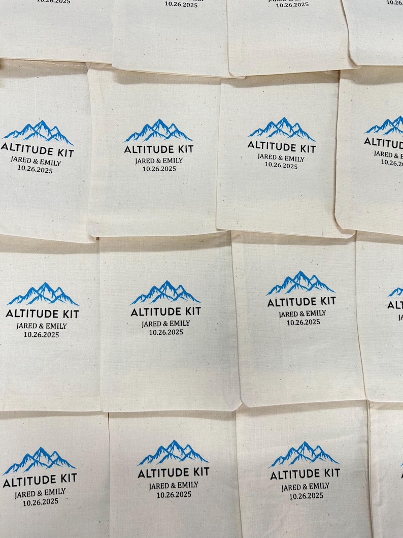 May include: Cream-coloured fabric pouches, each printed with a blue mountain design and the text "ALTITUDE KIT JARED & EMILY 10.26.2025". The pouches are arranged in a grid, ideal for event favours or gifts.