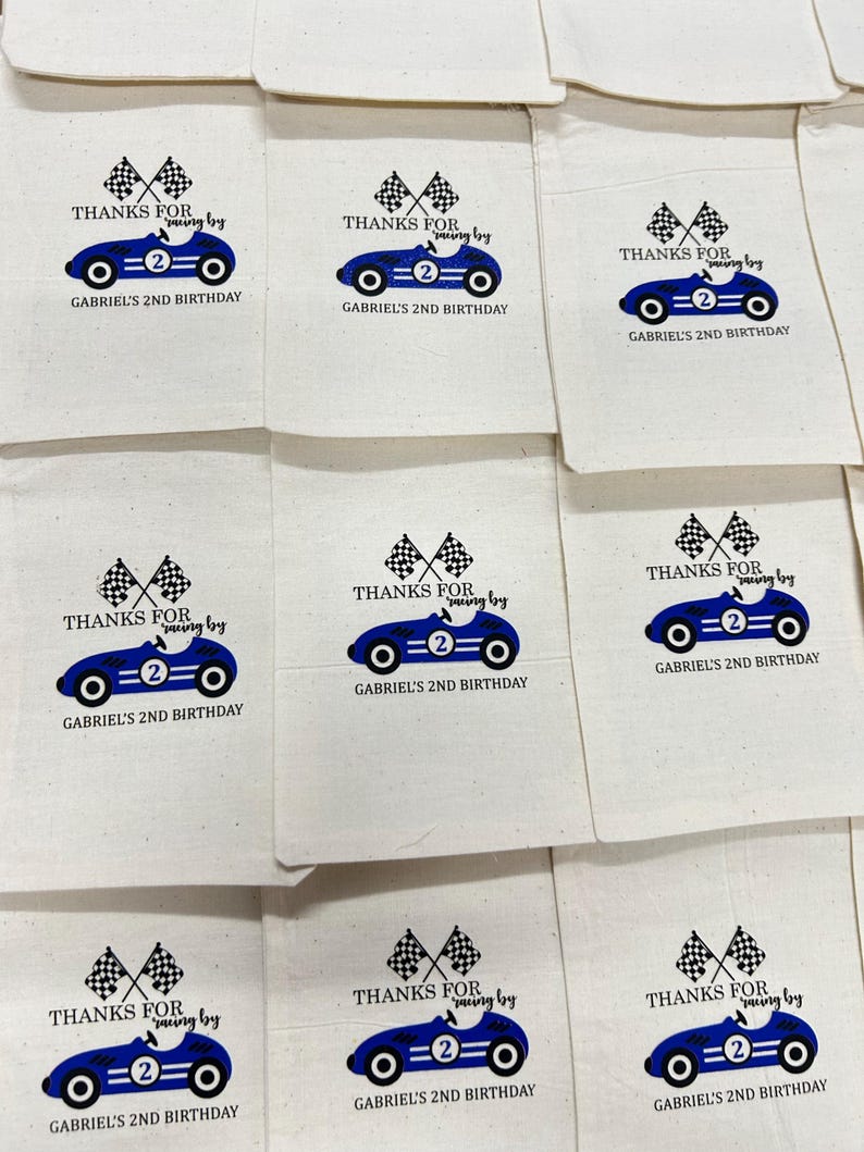 May include: Cream-coloured party bags featuring a blue racing car design, chequered flags, and the text "THANKS FOR racing by" and "GABRIEL'S 2ND BIRTHDAY". The bags are laid out in a grid.
