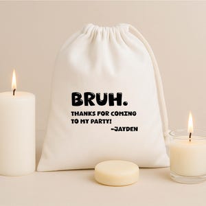 May include: A cream-colored fabric drawstring pouch featuring the black printed text: BRUH. THANKS FOR COMING TO MY PARTY! -JAYDEN. The pouch is positioned between two white pillar candles and a small round white wax disc on a neutral surface.
