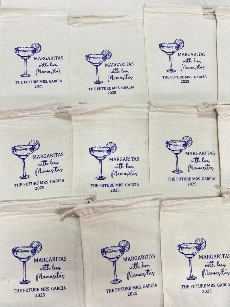May include: Cream-coloured drawstring bags featuring a blue margarita glass illustration and text. The text says "MARGARITAS with her Mamasitas THE FUTURE MRS. GARCIA 2025". These bags are suitable for a hen party or wedding.