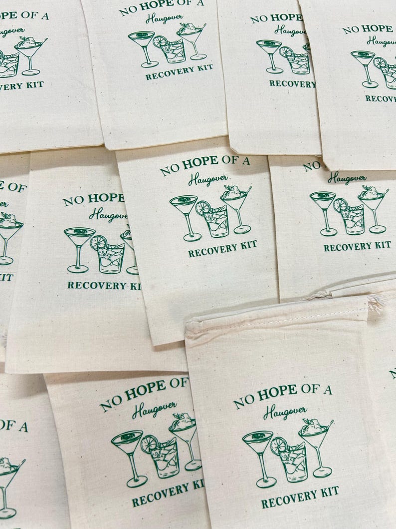 May include: Off-white canvas bags with a green illustration of cocktails and the text "NO HOPE OF A Hangover RECOVERY KIT". Several bags are visible, arranged in a pile.