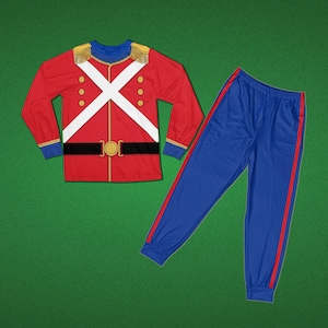 May include: A long-sleeve red shirt featuring a printed British guard uniform design with white cross-belts, gold epaulets, and a black belt with a gold buckle, paired with blue jogger pants that have a vertical red stripe down each side.