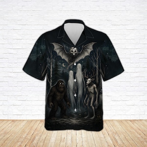 May include: A black short-sleeve button-down shirt featuring a dark forest graphic print. The design includes a large bat with a skull head, two tall white ghost figures, a brown hairy creature, and a skeletal deer-like figure in a night scene.