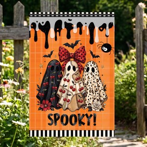May include: A rectangular garden flag with an orange plaid background featuring three ghosts. The left ghost is black with red cherries, the centre is cream with cherries and a large red polka dot bow, and the right is leopard print. Text reads SPOOKY!