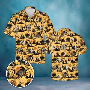 Op de afbeelding: Een overhemd met korte mouwen en knoopsluiting met een all-over Halloween-print op een gele achtergrond. Het patroon toont wasberen met heksenhoeden op bezemstelen, silhouetten van kale bomen, pompoenen en volle manen.