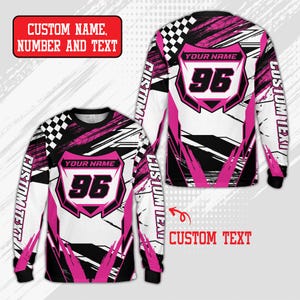 Puede incluir: Una camiseta de manga larga con un patrón gráfico abstracto en blanco, negro y rosa y un diseño de bandera a cuadros en el hombro. El frente y la espalda muestran un emblema central con el número 96 y el texto YOUR NAME.