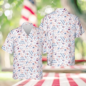 Puede incluir: Camisa blanca de manga corta con un estampado patriótico. El diseño incluye fuegos artificiales, estrellas, banderas y el texto "USA", "July" y "250 Years of Freedom" en rojo y azul. La camisa tiene botones.