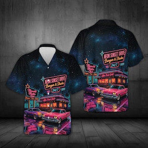 Puede incluir: Una camisa de manga corta con botones, estampado de galaxia azul oscuro y una escena de restaurante con luces de neón. El gráfico incluye un coche clásico rosa, palmeras y el texto Neon Sunset Drive Burger & Shake 24/7 y Moonlit Motor Club.
