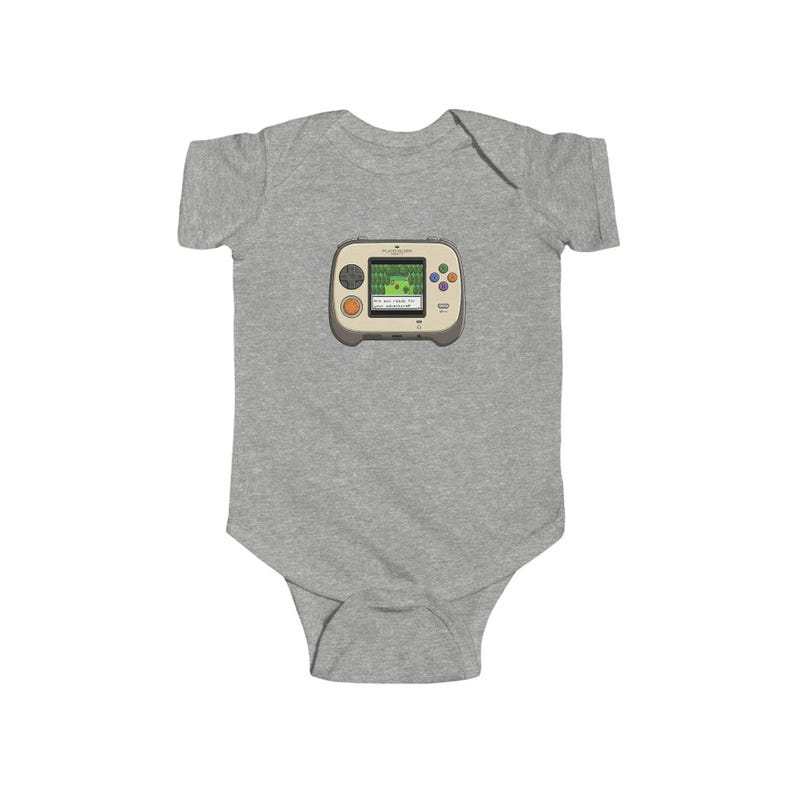 May include: A gray baby bodysuit featuring a retro handheld video game graphic. The game console is beige with colorful buttons and a green screen displaying a pixelated landscape. The bodysuit is made of soft fabric.