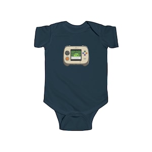 May include: Navy blue baby bodysuit featuring a retro handheld video game graphic. The game console is beige with a green screen displaying a pixelated landscape. It has orange and colorful buttons. A cute and playful design for a baby.